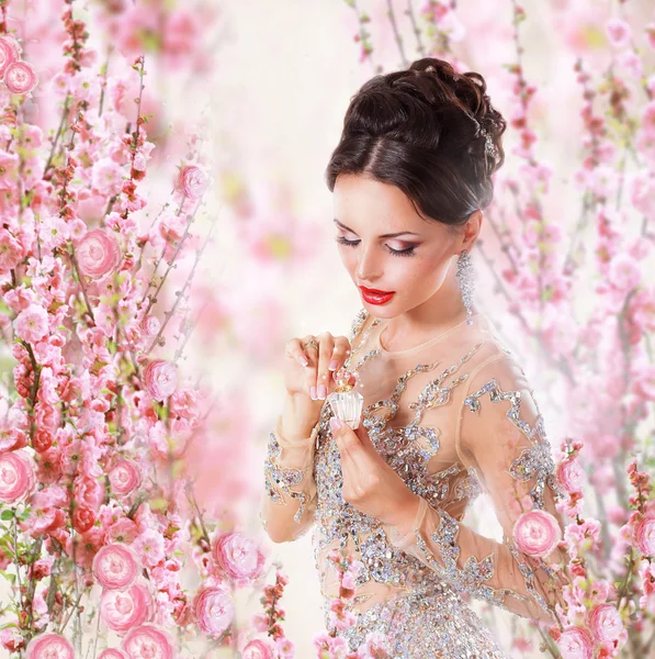 Mulher com perfume sobre fundo floral — Fotografia de Stock
