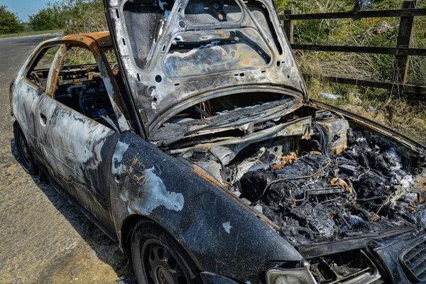 Un coche abandonado que ha sido incendiado y quemado. — Foto de Stock