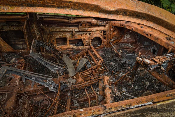 Rusty quemado coche mostrando dentro de la devastación causada por el fuego — Foto de Stock