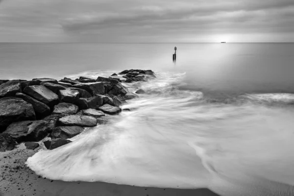 Onde lattiginose che schizzano sulle rocce in bianco e nero — Foto Stock