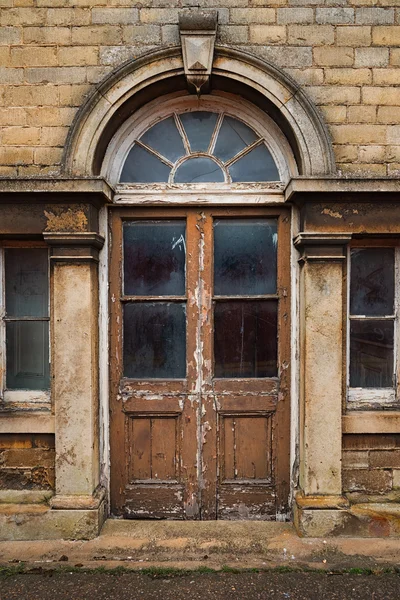 Vecchio decadente porte doppie in legno in un arco di pietra — Foto Stock