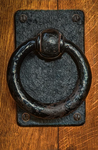 Old black metal circular knocker on oak door