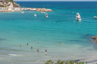 Orihuela Costa, İspanya - 16 Haziran 2018: İnsanlar Cabo Roig 'deki Cala Capitan plajında güneşleniyor ve yüzüyorlar. Alicante vilayeti. Costa Blanca 'da. İspanya.