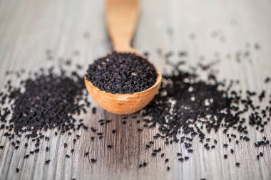 Kurumuş kimyon tohumlarını yakın plan çekimde ahşap arka planda tahta kaşık üzerinde kalinji. Yumuşak odak.