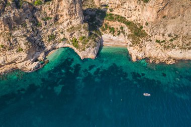 Birkaç turistle birlikte iki kayalık burnun arasında korunan gizli kumsalın insansız hava aracı görüntüsü. Yaz güneşli bir gün. Cala Moraig, Valencia topluluğu, İspanya
