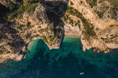 Birkaç turistle birlikte iki kayalık burnun arasında korunan gizli kumsalın insansız hava aracı görüntüsü. Yaz güneşli bir gün. Cala Moraig, Valencia topluluğu, İspanya