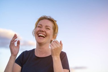 Genç, beyaz, beyaz, kumsalda gülümseyen ve gülen bir kadın..