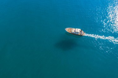 Güneşli bir günde Akdeniz 'in sığ sularında yüzen küçük balıkçı teknesi fotokopi uzayı ile havadan çekiliyor..