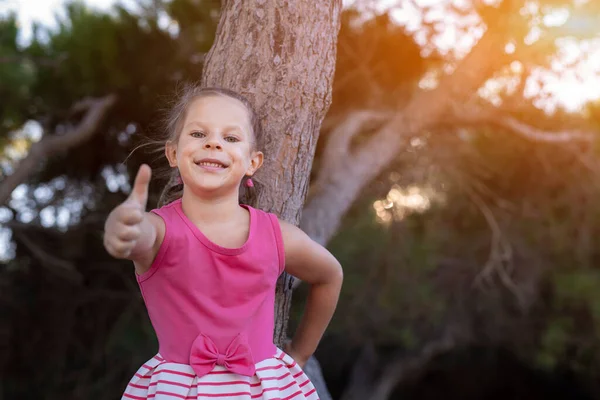 一个可爱迷人的小女孩的肖像画 她在公园里大显身手 背景是黑树 — 图库照片