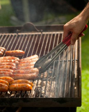 Bahçede ya da arka bahçede kömürlü barbekü ızgarası. Bir sürü dumanlı sosis..