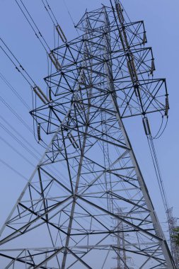 Mavi gökyüzü arka planında yüksek voltajlı elektrik direği.