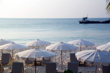 Akşam kumsalı arka planında şemsiyelerin altında boş güneşlikler..