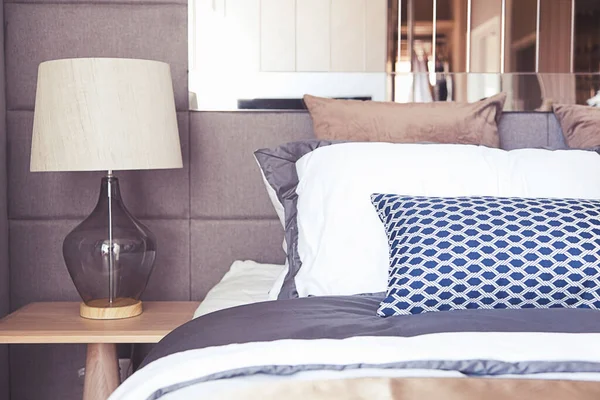 Çağdaş iç tasarımı olan modern yatak odası, rahat yatağın üzerinde lamba ışığı.