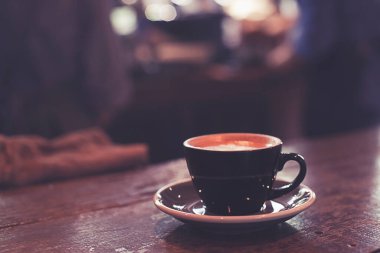 Arka planda garson kadın olan kahve tezgahının üzerinde sıcak kahve fincanı..