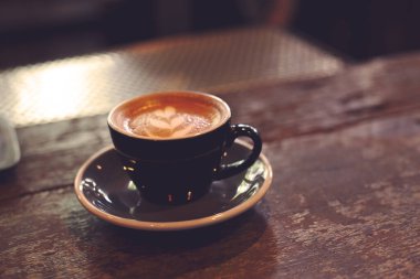 Arka planda garson kadın olan kahve tezgahının üzerinde sıcak kahve fincanı..