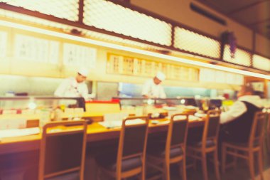 Suşi restoranının arka planı bulanık. Şef suşi barının arkasında suşi yapıyor.