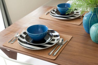 Modern evdeki dekoratif vazo ile yemek masasında modern tabak seti..