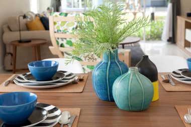 Modern evdeki dekoratif vazo ile yemek masasında modern tabak seti..