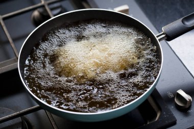 Deep fried tofu in a pan with the boiling oil. Cooking in kitchen.