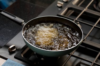 Deep fried tofu in a pan with the boiling oil. Cooking in kitchen.