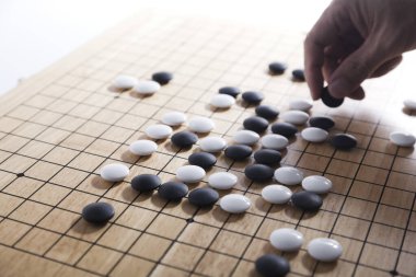 Oyuncu eli oyun tahtasına taş koydu. Eski bir oyun. Korece baduk, Çince weiqi ve Japonca Igo olarak da bilinir..