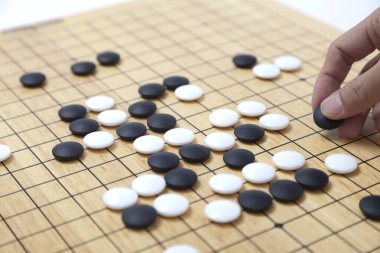 Oyuncu eli oyun tahtasına taş koydu. Eski bir oyun. Korece baduk, Çince weiqi ve Japonca Igo olarak da bilinir..
