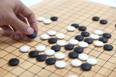 Oyuncu eli oyun tahtasına taş koydu. Eski bir oyun. Korece baduk, Çince weiqi ve Japonca Igo olarak da bilinir..