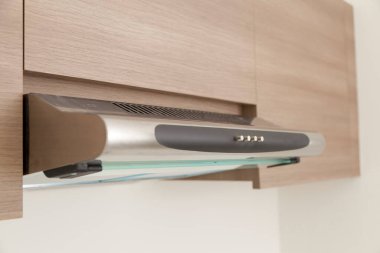 Dolap kapağının, egzoz kapağının, modern elektrikli ocağın, gri ve beyaz mutfak tasarımlı fırının altında yakın çekim..