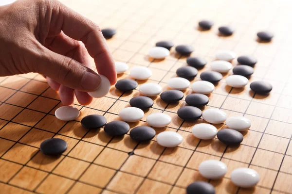 player\'s hand put stone on the game board - an ancient game also known as baduk in Korean, weiqi in Chinese and Igo in Japanese.