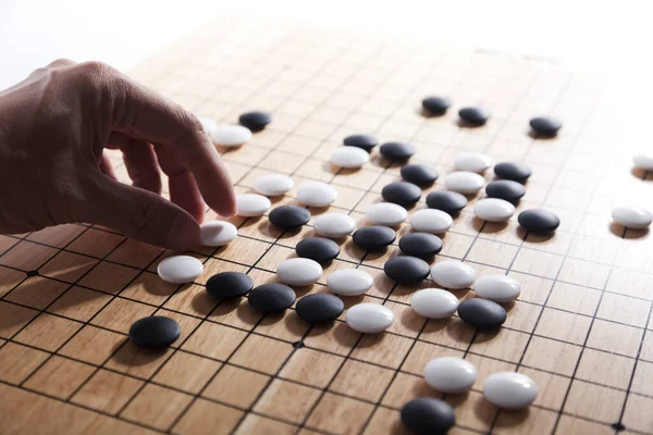 player\'s hand put stone on the game board - an ancient game also known as baduk in Korean, weiqi in Chinese and Igo in Japanese.