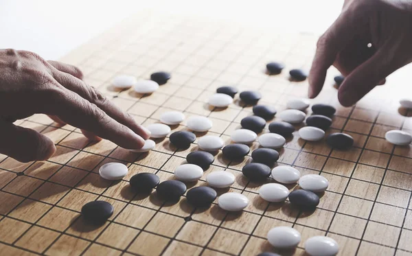 Oyuncu eli oyun tahtasına taş koydu. Eski bir oyun. Korece baduk, Çince weiqi ve Japonca Igo olarak da bilinir..