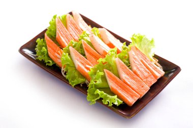 Beyaz arka planda bir tabakta saşimi yengeci çubuğu.