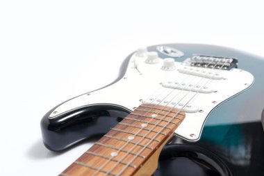 Humbucker pikaplı siyah elektro gitar, yakın çekim. Beyaz duvar arkaplanındaki müzikal enstrüman şekli.