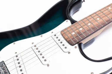 Humbucker pikaplı siyah elektro gitar, yakın çekim. Beyaz duvar arkaplanındaki müzikal enstrüman şekli.