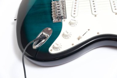 Humbucker pikaplı siyah elektro gitar, yakın çekim. Beyaz duvar arkaplanındaki müzikal enstrüman şekli.