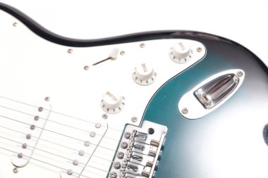 Humbucker pikaplı siyah elektro gitar, yakın çekim. Beyaz duvar arkaplanındaki müzikal enstrüman şekli.