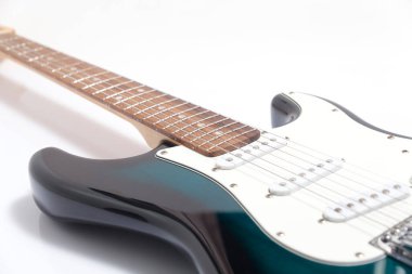 Humbucker pikaplı siyah elektro gitar, yakın çekim. Beyaz duvar arkaplanındaki müzikal enstrüman şekli.