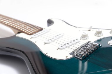 Humbucker pikaplı siyah elektro gitar, yakın çekim. Beyaz duvar arkaplanındaki müzikal enstrüman şekli.