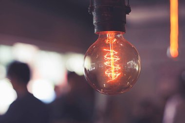 Karanlık odada sarkan parlak ampullerin yakın çekimi. Düz telli dekoratif antika Edison ampulleri. Küçültülebilir, ılık beyaz, E27