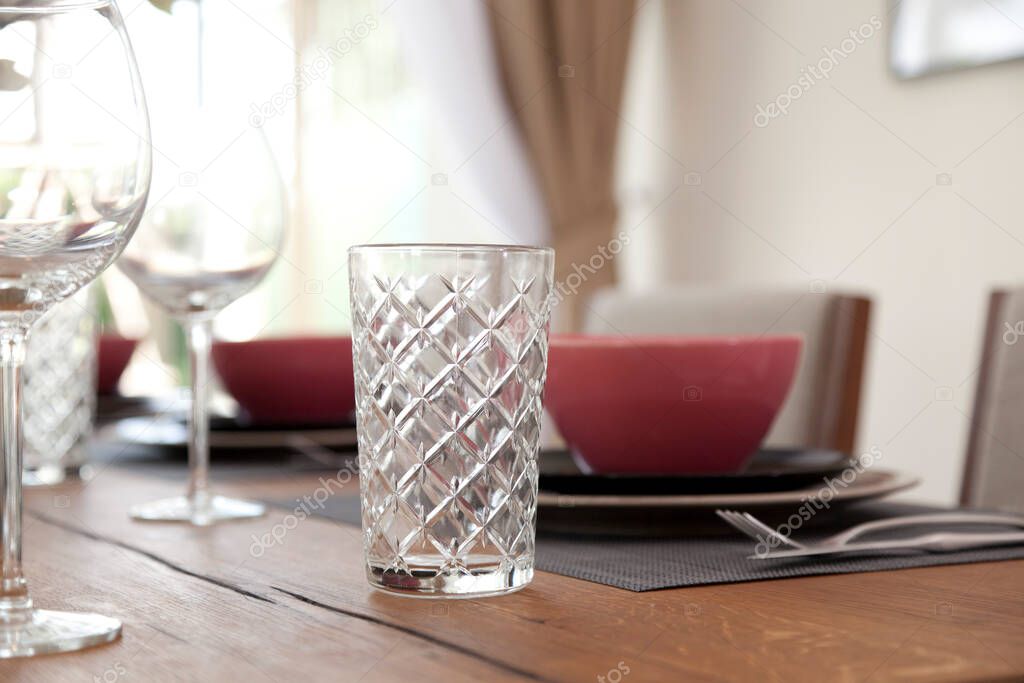 Close up of glass  and plate on dining table with table set in modern dining room . Interior design concept.