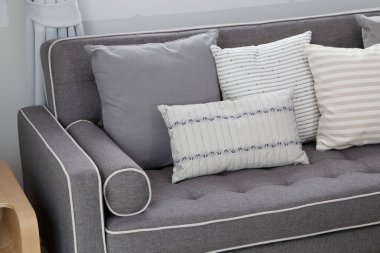 Modern oturma odasının içinde gri koltukta siyah beyaz yastıklar var..