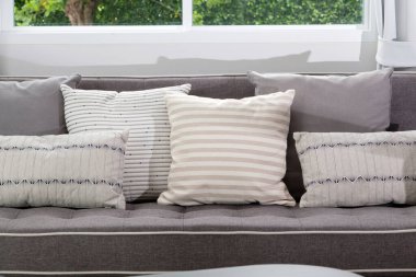 Modern oturma odasının içinde gri koltukta siyah beyaz yastıklar var..