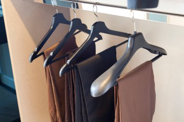 Dolaptaki askılarda asılı şık pantolon koleksiyonu.