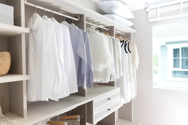 Erkek gömlekleri ve kadın giysileri evdeki ahşap gardıropta asılı..