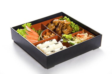 Japon usulü öğle yemeği kutusunda çeşitli sebzeler ve beyaz arka planda etler.