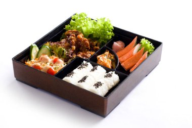 Japon usulü öğle yemeği kutusunda çeşitli sebzeler ve beyaz arka planda etler.