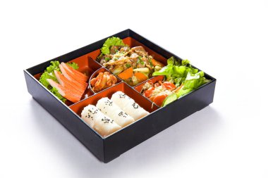 Japon usulü öğle yemeği kutusunda çeşitli sebzeler ve beyaz arka planda etler.