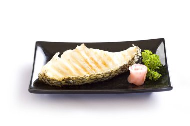 Beyaz arka planda siyah tabakta tuzlu ızgara somon bifteği..