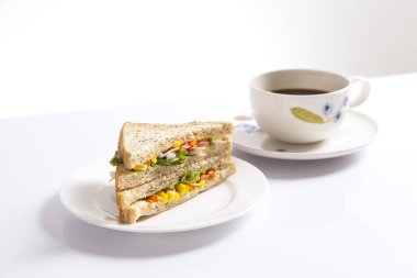 Beyaz arka planda bir fincan kahveli ızgara sandviç..