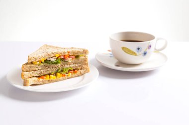 Beyaz arka planda bir fincan kahveli ızgara sandviç..